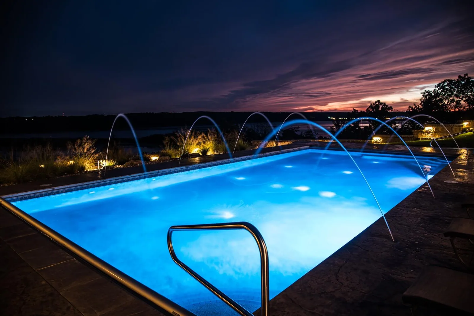 Custom pool lit at dusk with LED lighting and a stone surround