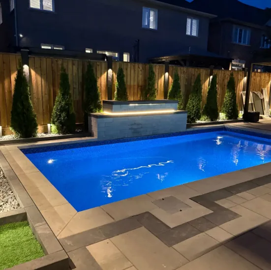 Pool lit at night with an illuminated water feature wall