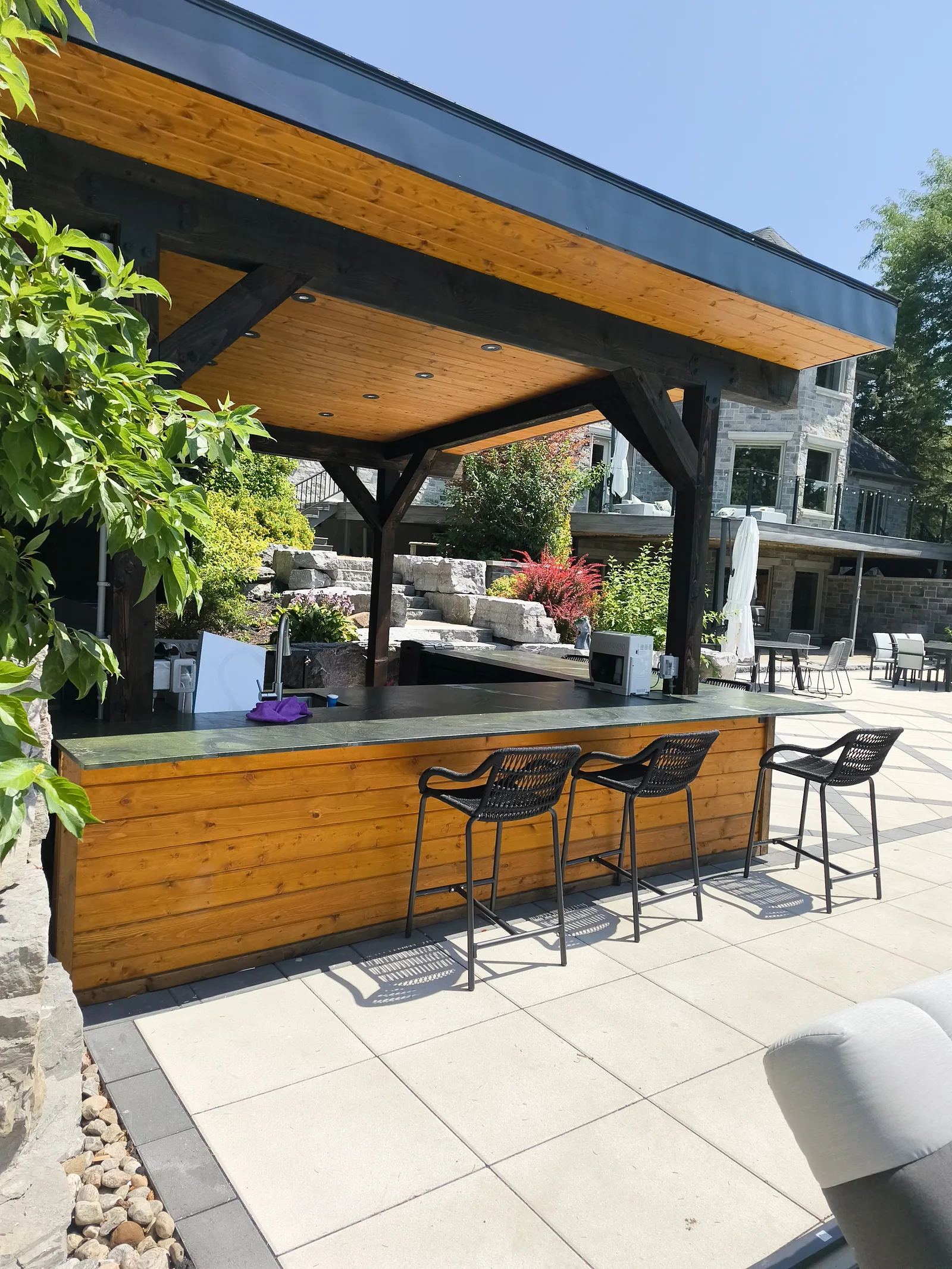 Covered outdoor kitchen and bar with seating beside the pool
