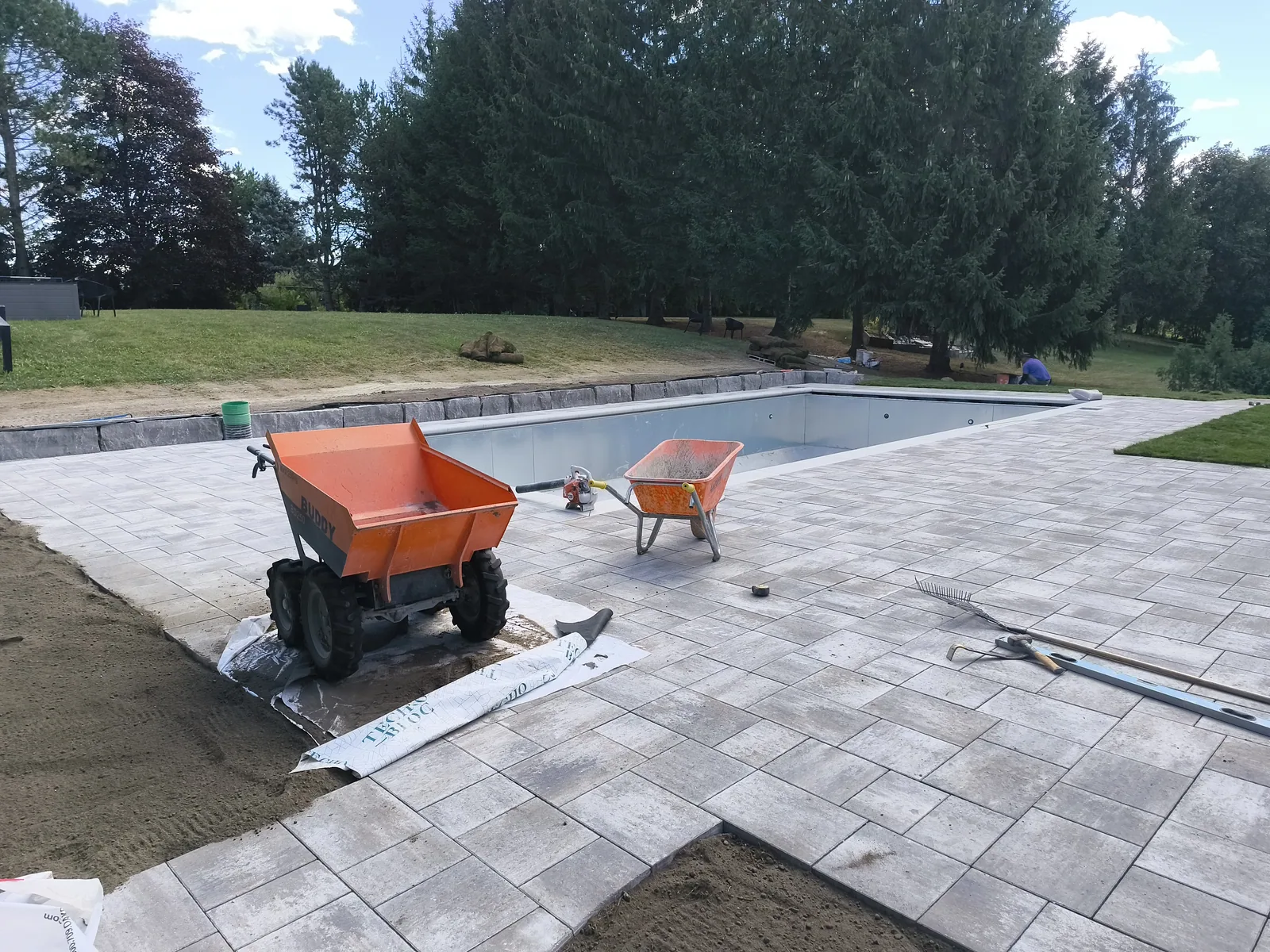 Paver deck being laid around a newly finished pool